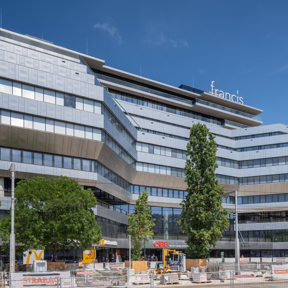 Außenansicht des Bürogebäudes Francis im Althan Quartier Wien mit moderner silberner Glasfassade, großen Fensterflächen und Bäumen im Vordergrund | © © Walter Luttenberger