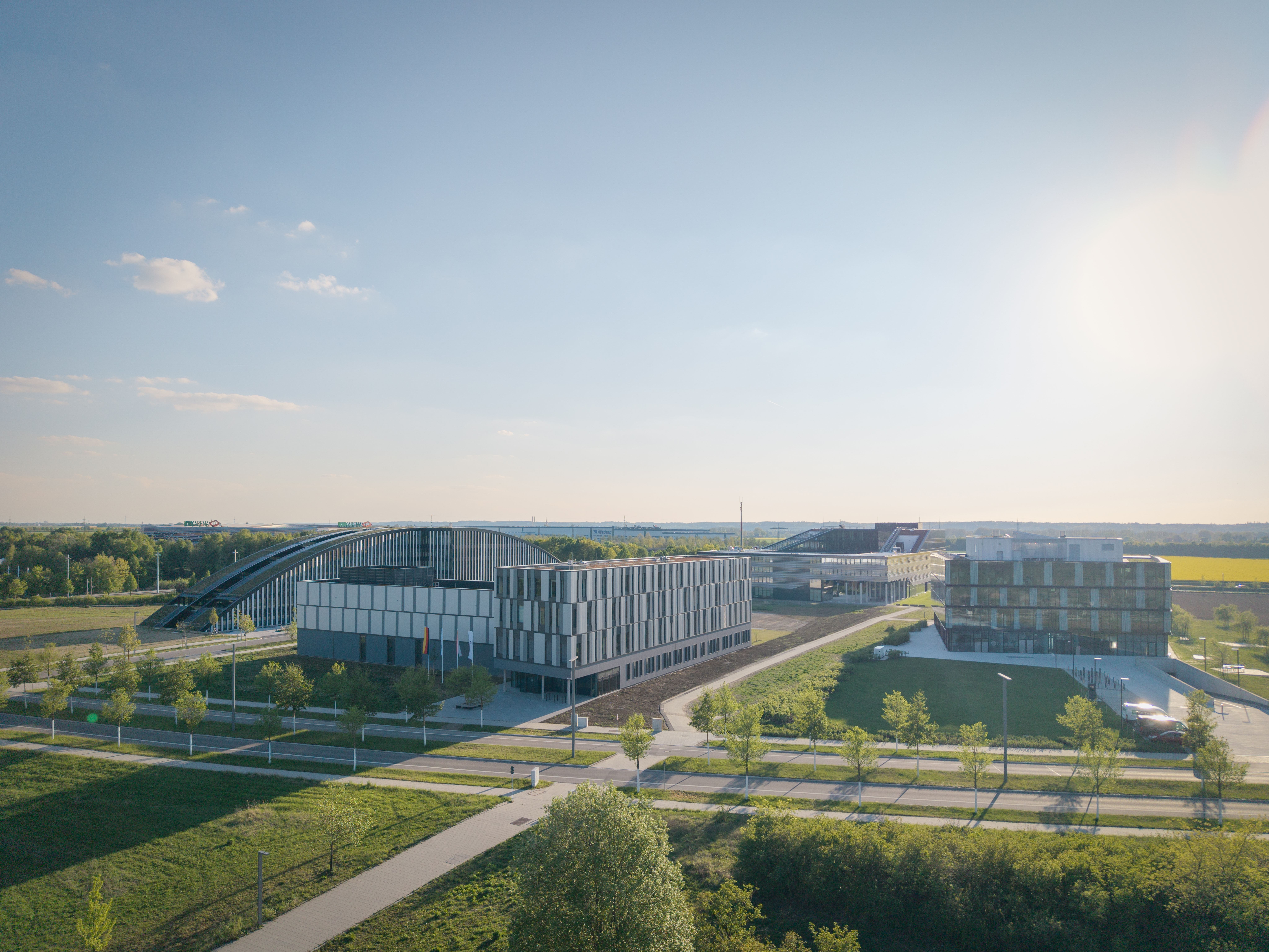 Drohnenaufnahme des DLR-Institutsgebäudes im Technologiepark Augsburg mit modernen Forschungs- und Büroflächen, umgeben von begrünten Außenanlagen unter sonnigem Himmel | © © www.Lindner-Group.com