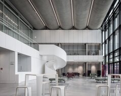 Modernisiertes Foyer des Helmholtz Zentrums München mit geschwungener Treppe, großflächiger Verglasung und modernen Sitzbereichen. | © © www.Lindner-Group.com