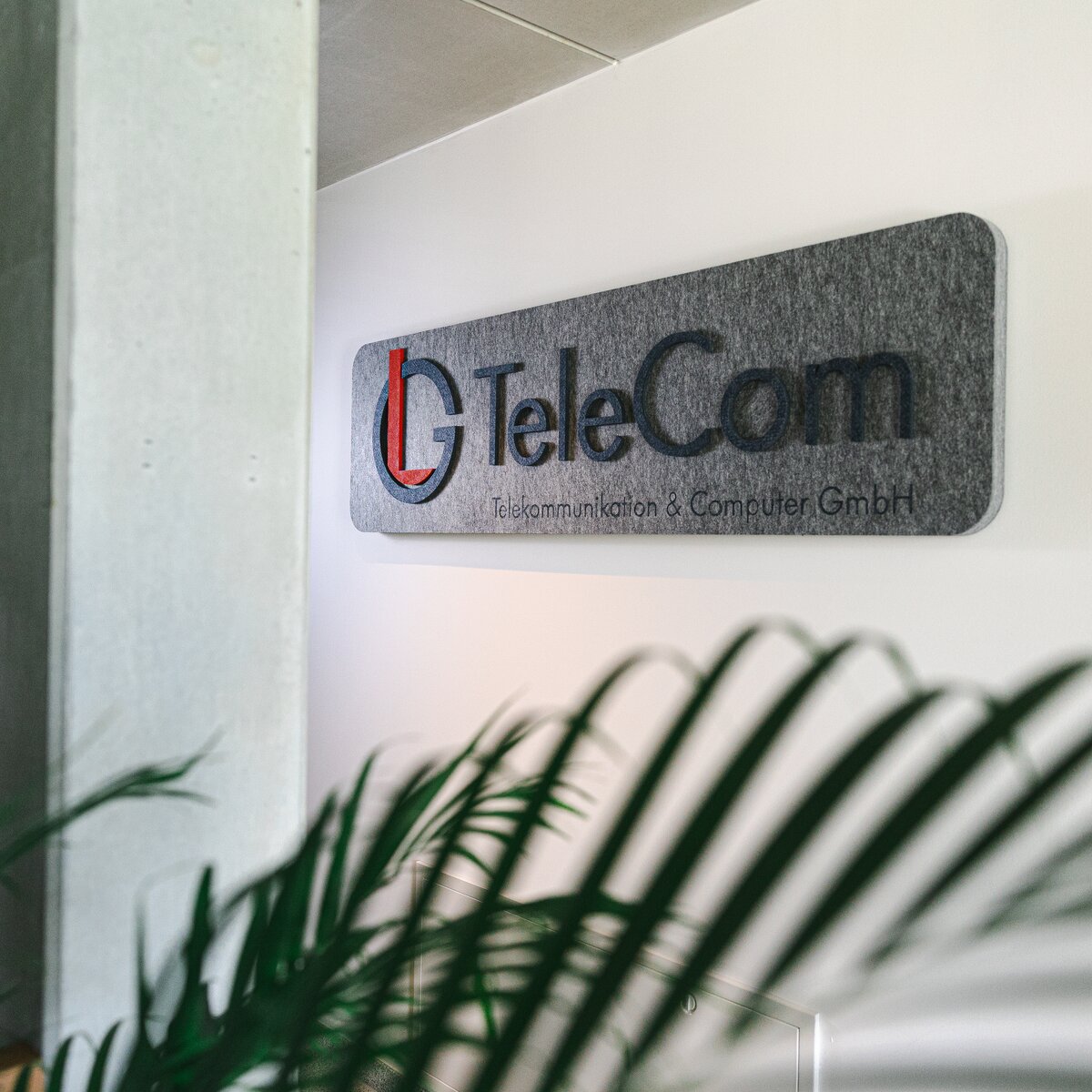 Grauer MUTE+® board Schallabsorber mit aufgedrucktem LG TeleCom Logo an der Wand – individuelle Akustiklösung von Lindner für markenstarke Raumgestaltung. | © © www.Lindner-Group.com