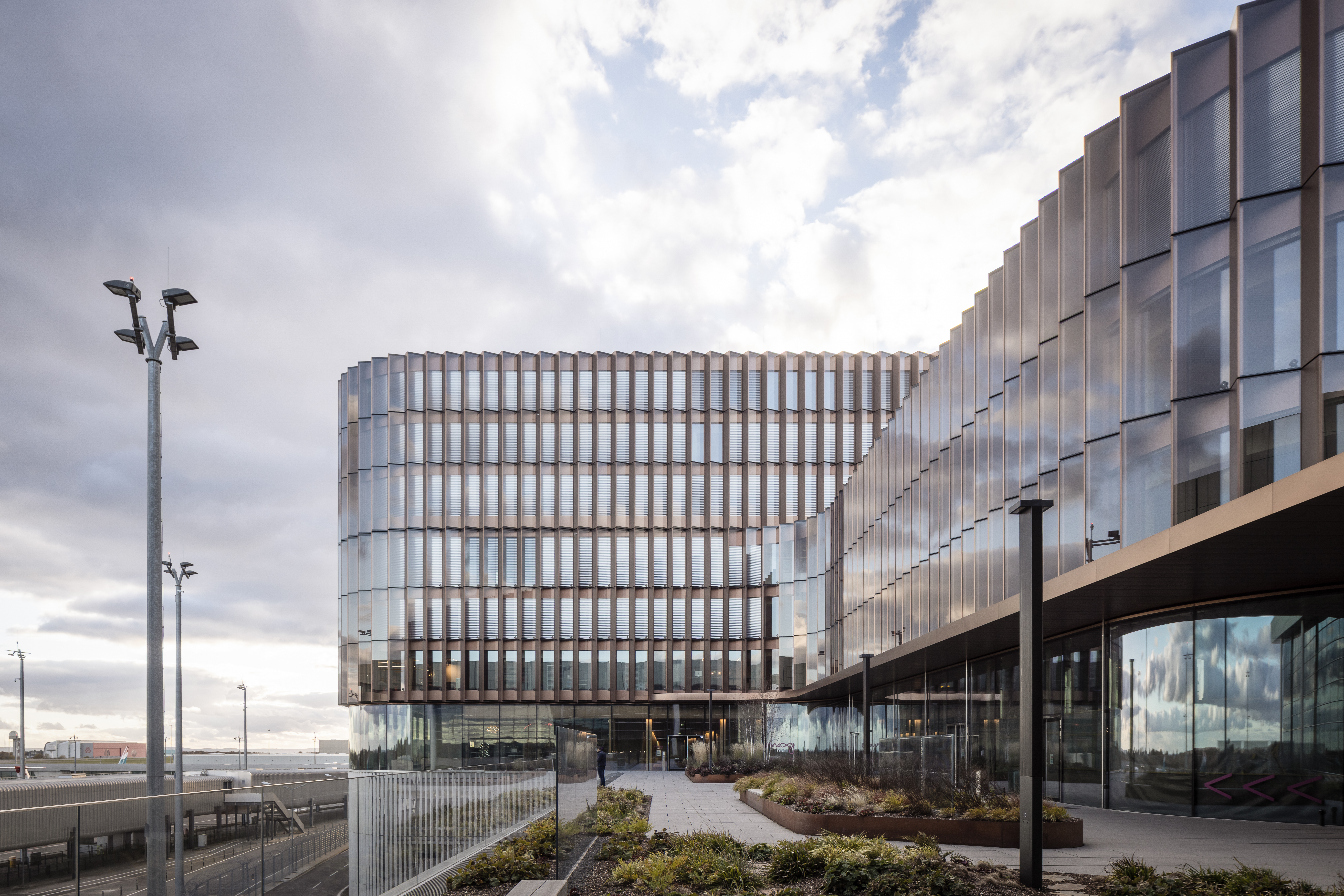Skypark Business Center Findel Luxemburg mit kupferfarbener Fassade, Glasfront, Lindner Innenausbauprodukten und Flughafen Luxemburg im Hintergrund | © © www.Lindner-Group.com